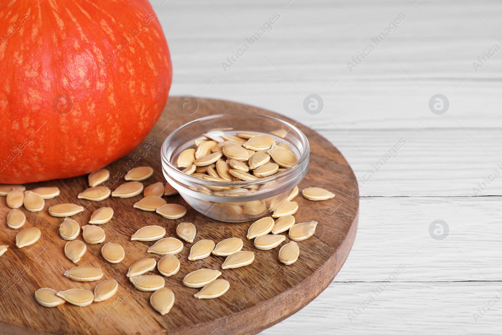 Photo of Fresh pumpkin and vegetable seeds on white wooden table, closeup. Space for text