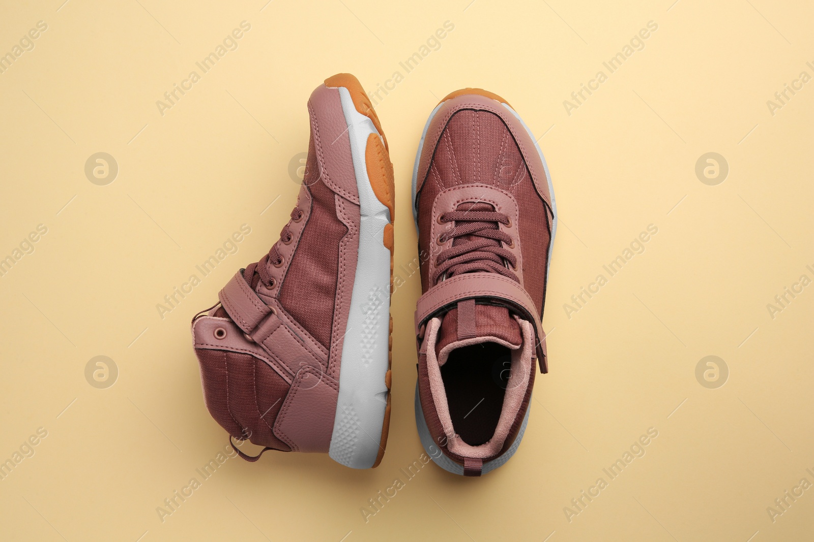 Photo of Pair of stylish kid's sneakers on beige background, top view