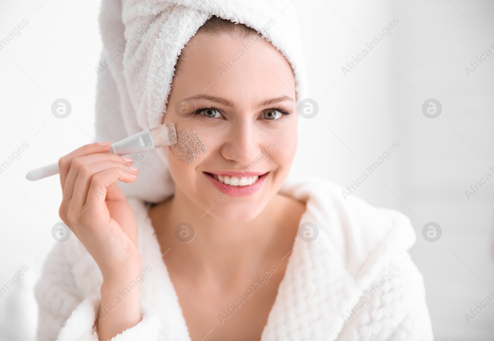 Photo of Woman applying scrub onto face in bathroom