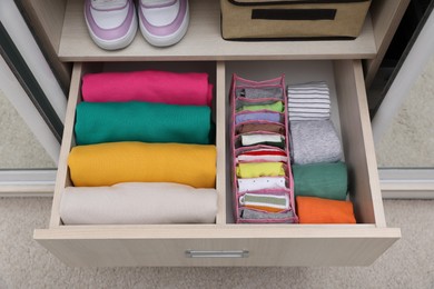Photo of Wardrobe drawer with folded clothes and shoes, above view. Vertical storage