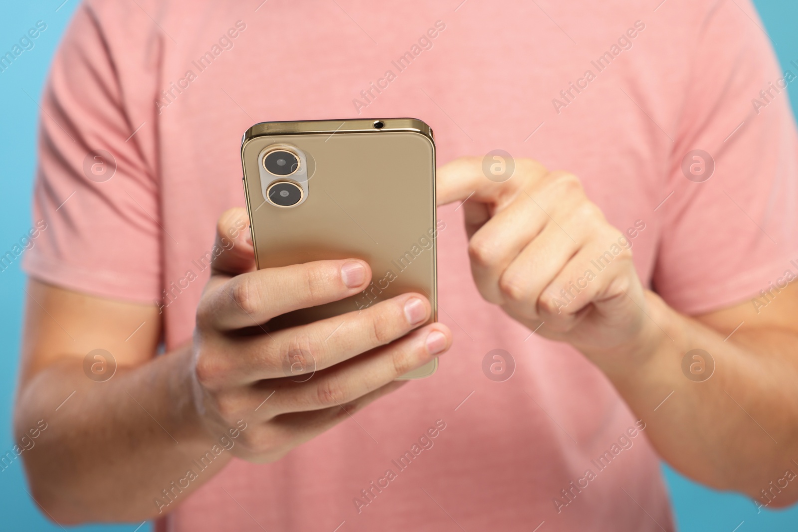 Photo of Man sending message via smartphone on light blue background, closeup