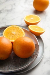 Plate with fresh juicy oranges on marble table