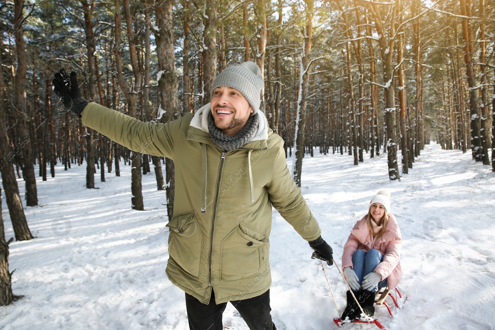 Photo of Man pulling his girlfriend in sleigh outdoors on winter day