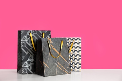 Photo of Gift bags on white table against pink background
