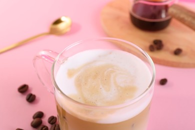 Photo of Cup of fresh coffee and beans on pink table, closeup
