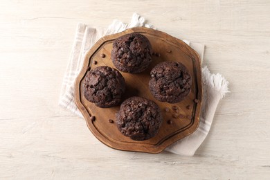 Photo of Delicious chocolate muffins on white wooden table, top view