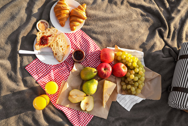 Picnic blanket with delicious food and juice outdoors on sunny day, top view