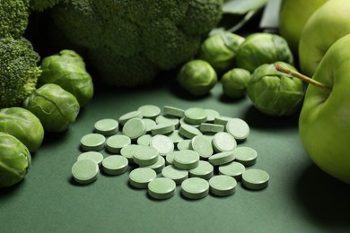 Photo of Pile of pills and food on green background. Prebiotic supplements