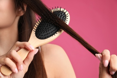 Woman with hair brush on color background, closeup