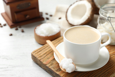 Photo of Delicious coffee with organic coconut oil on white wooden table