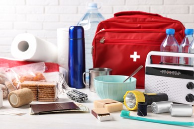 Photo of Disaster supply kit for earthquake on white wooden table near brick wall
