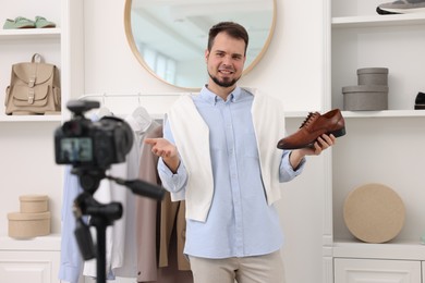 Smiling fashion blogger showing shoe while recording video at home