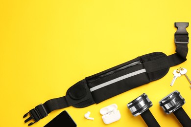 Photo of Flat lay composition with stylish black waist bag on yellow background, space for text