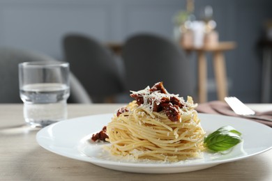 Photo of Tasty spaghetti with sun-dried tomatoes and parmesan cheese on wooden table in restaurant, closeup. Exquisite presentation of pasta dish