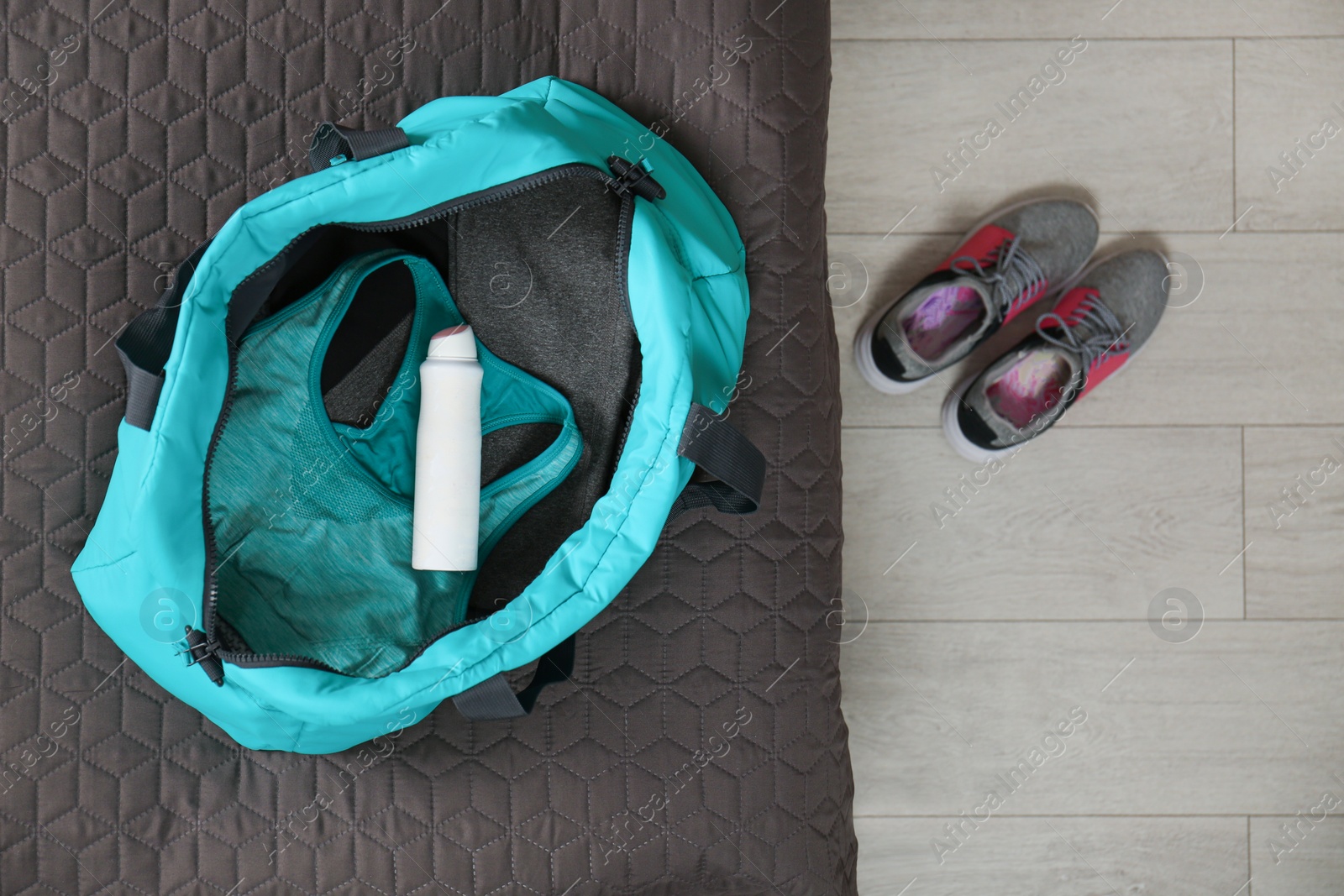 Photo of Deodorant in gym bag on bed, top view