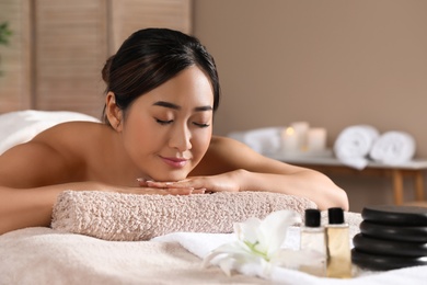 Photo of Beautiful Asian woman lying on massage table in spa salon. Space for text