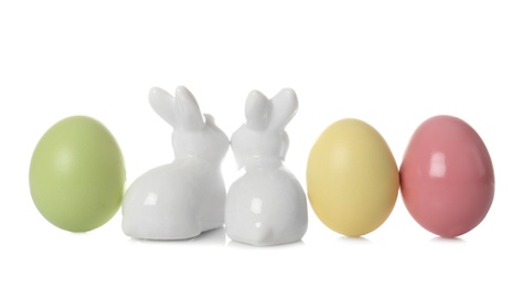 Cute ceramic Easter bunnies and dyed eggs on white background