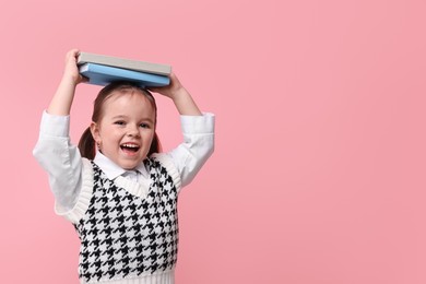 Photo of Cute little girl with books on pink background. Space for text