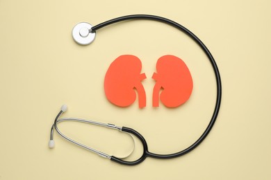 Paper cutout of kidneys and stethoscope on beige background, flat lay