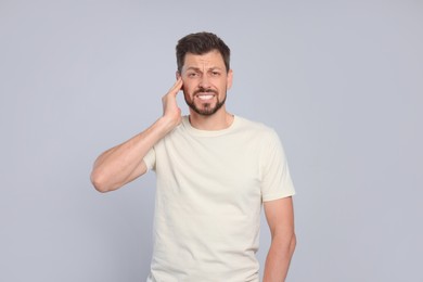 Photo of Man suffering from ear pain on grey background