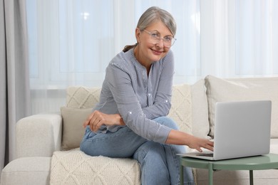 Beautiful senior woman using laptop at home