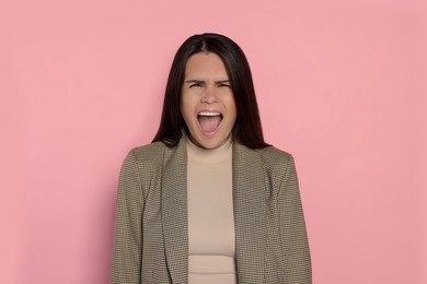 Photo of Aggressive young woman shouting on pink background