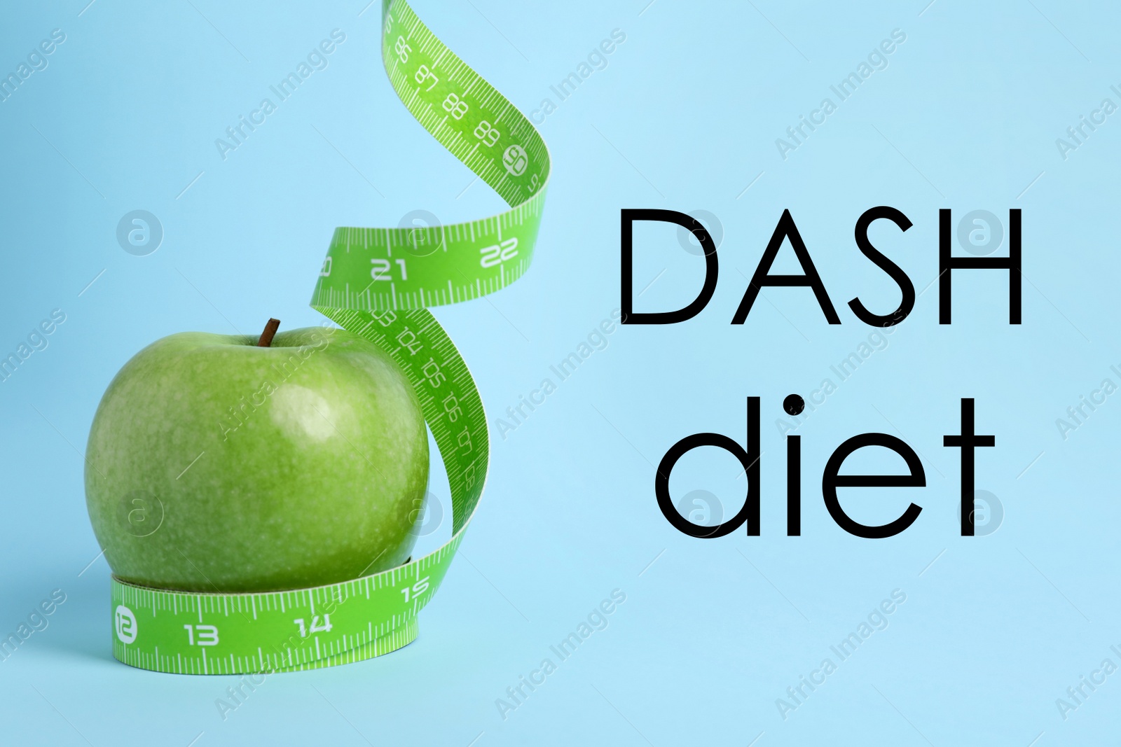 Image of DASH diet to stop hypertension. Ripe green apple and measuring tape on light blue background