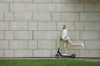 Photo of Businessman riding modern kick scooter near grey stone wall outdoors, space for text