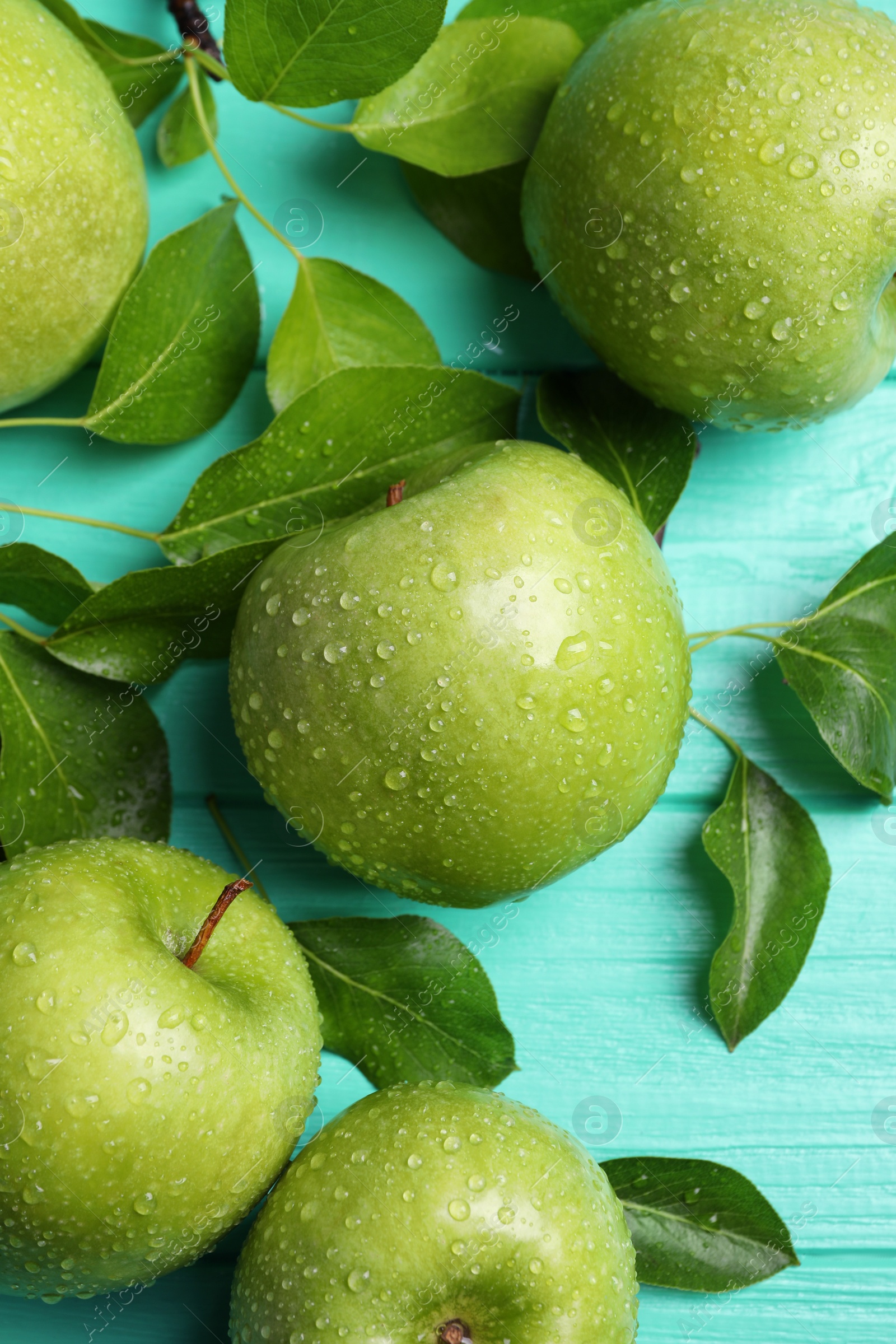 Photo of Fresh ripe green apples with water drops on turquoise wooden table, flat lay