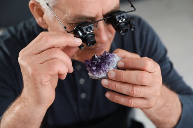 Photo of Male jeweler evaluating semi precious gemstone in workshop, closeup