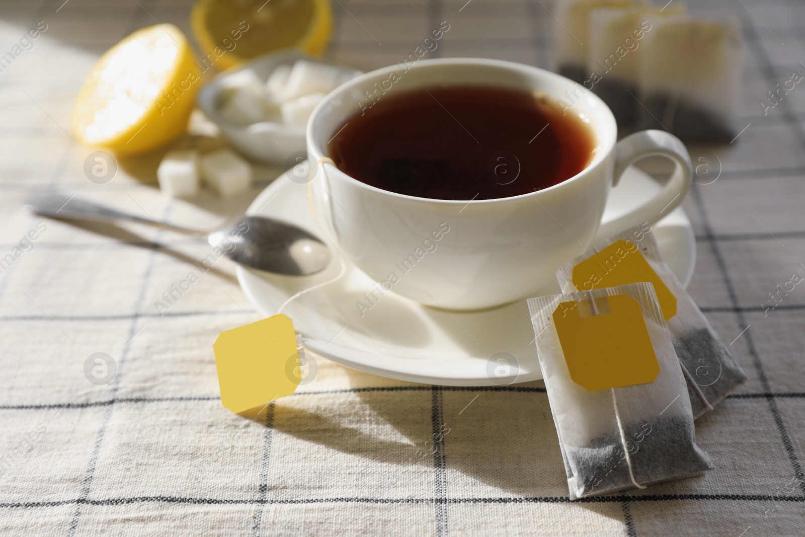 Photo of Tea bags near cup of hot drink on table, closeup