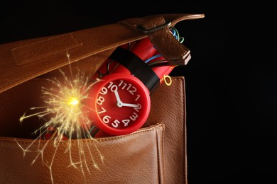 Dynamite time bomb with burning wires in bag on black background