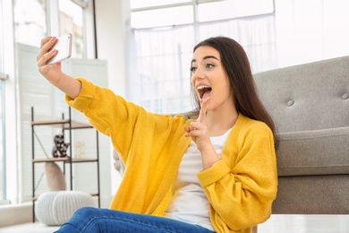 Photo of Beautiful young woman taking selfie at home