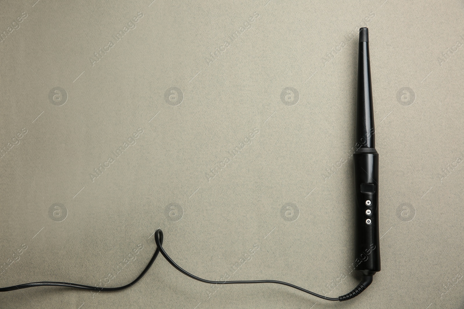 Photo of Modern clipless curling hair iron on grey background, top view. Space for text