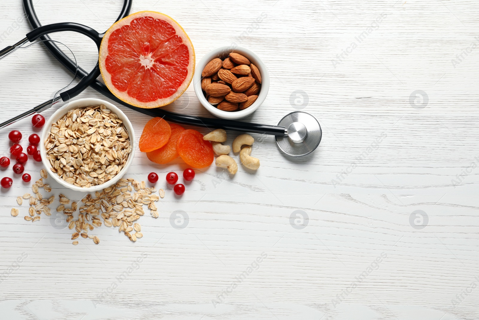 Photo of Heart-healthy products and stethoscope on wooden background, flat lay. Space for text