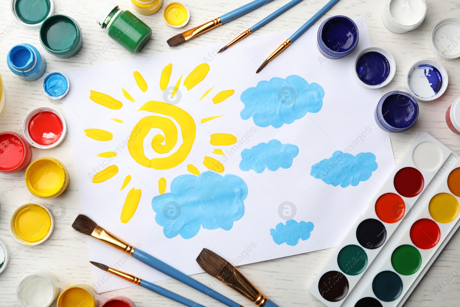 Photo of Flat lay composition with child's painting of sun and clouds on white wooden table