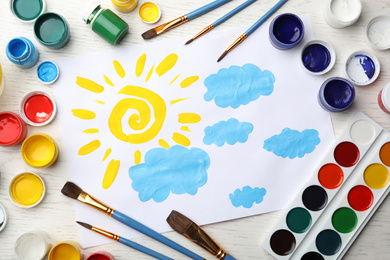 Photo of Flat lay composition with child's painting of sun and clouds on white wooden table