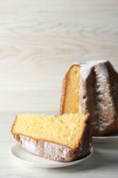 Delicious Pandoro cake decorated with powdered sugar on white wooden table. Traditional Italian pastry