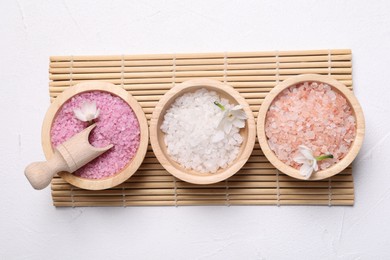 Different types of sea salt and flowers on light table, flat lay. Spa products