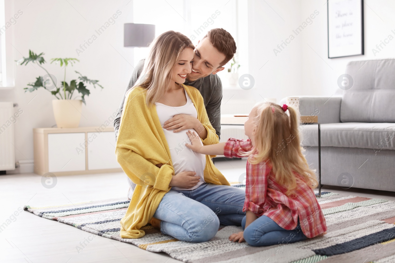 Photo of Young pregnant woman with her family at home