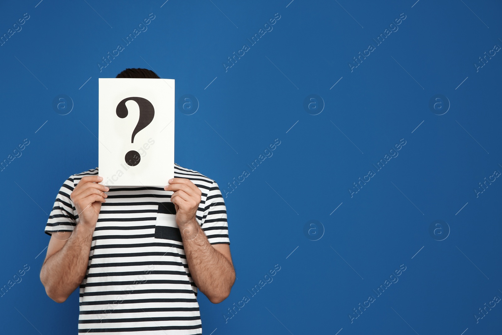 Photo of Man holding question mark sign on blue background. Space for text