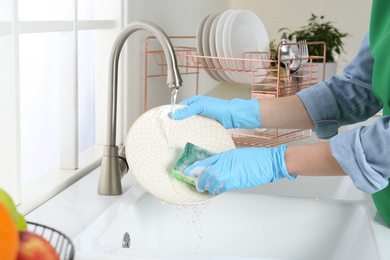 Woman washing plate in modern kitchen, closeup