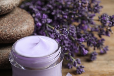 Photo of Stones, jar of cream and lavender flowers on table, closeup