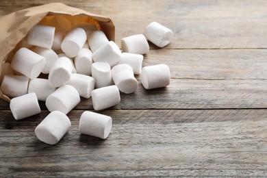 Photo of Delicious puffy marshmallows on wooden table, closeup. Space for text