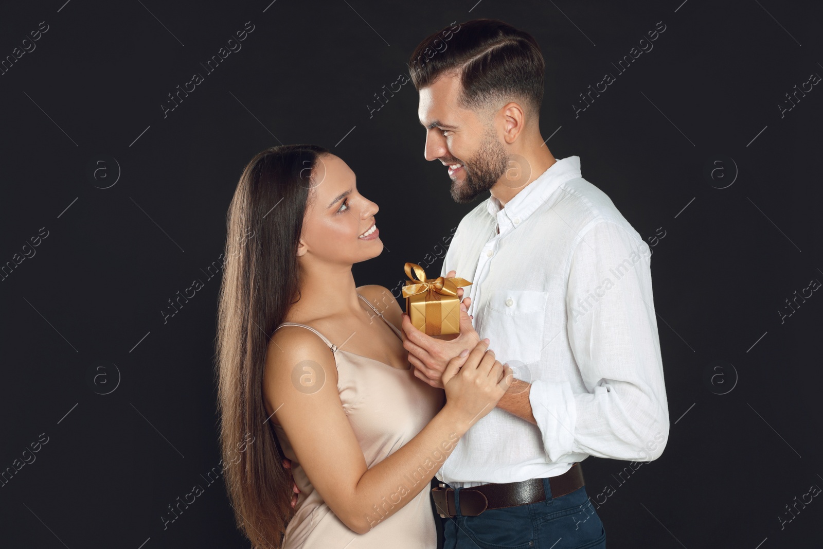 Photo of Lovely couple with gift on black background