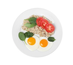 Delicious boiled oatmeal with fried eggs, tomato and basil isolated on white, top view