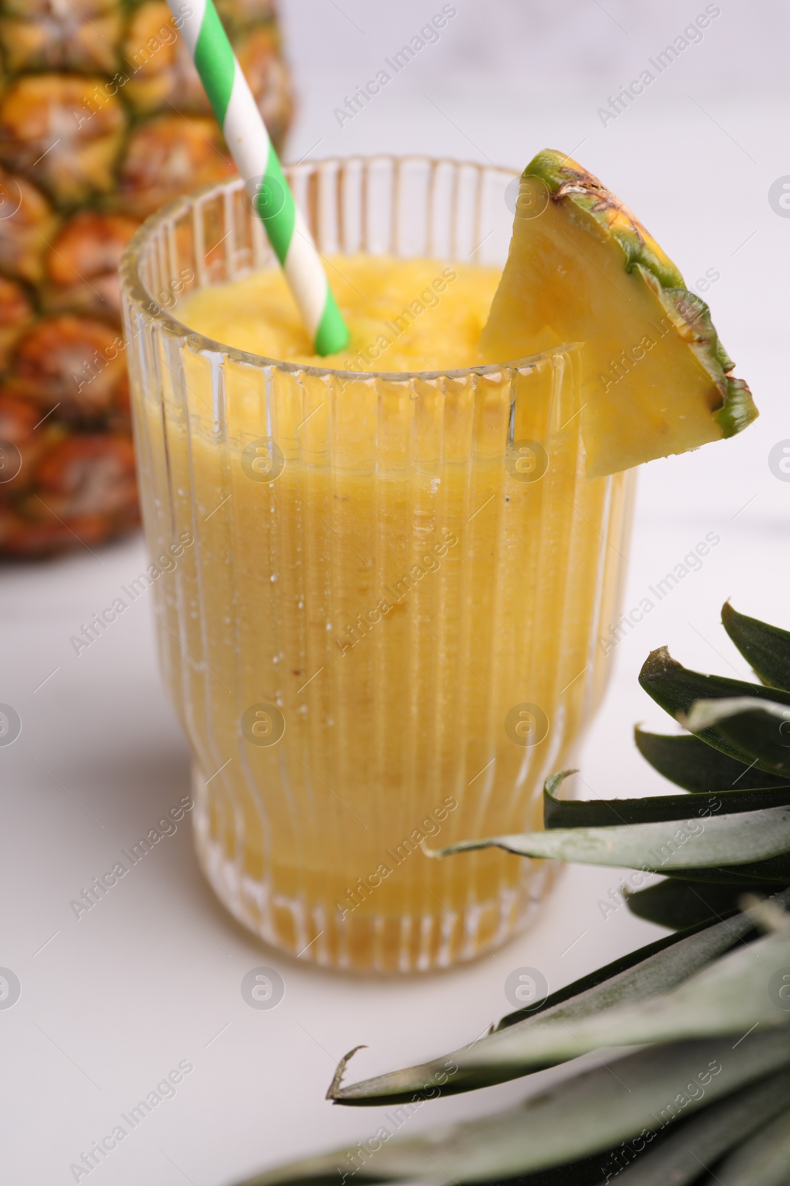 Photo of Tasty pineapple smoothie on white table, closeup