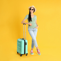 Beautiful woman with suitcase for summer trip on yellow background. Vacation travel