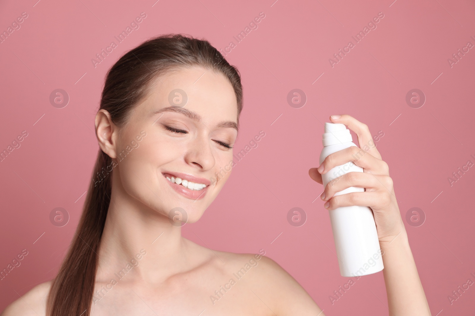 Photo of Young woman with bottle of thermal water on color background. Cosmetic product