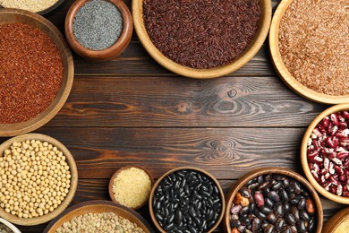 Frame of different grains and seeds on wooden table, flat lay with space for text. Veggie diet